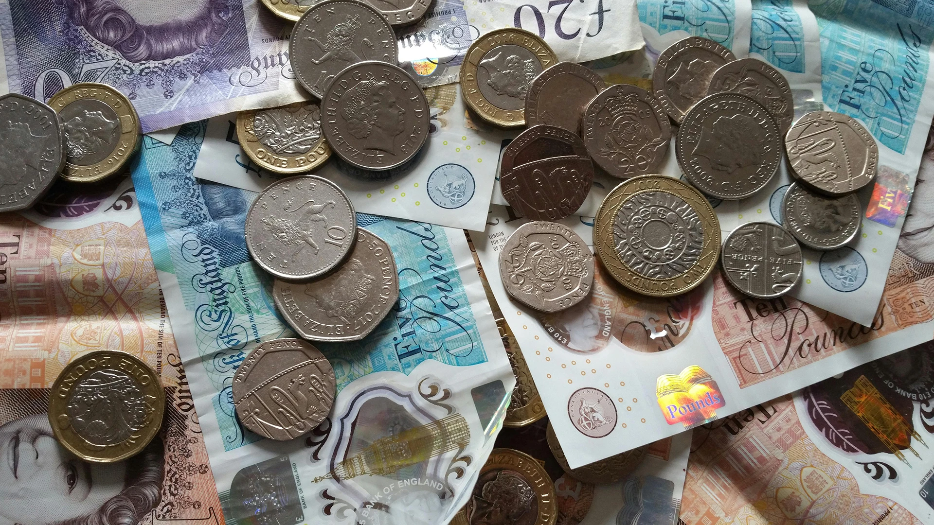 Close-up of British pound coins and banknotes scattered on a surface, symbolising financial loss or potential revenue impacted by slow website load times.