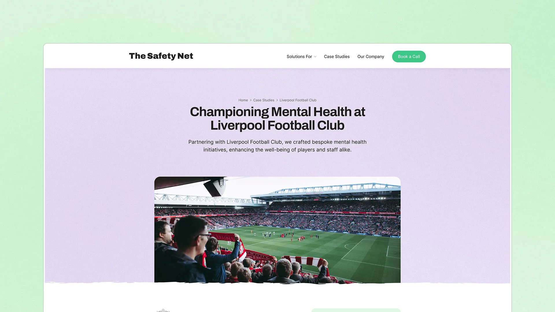 Web page section for The Safety Net, titled 'Championing Mental Health at Liverpool Football Club,' showing a case study with an image of Anfield Stadium and a crowd watching a game.